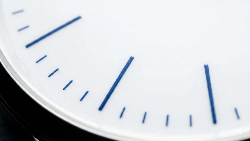 磁器で作られた真っ白な文字盤と青い針を持つシンプルで美しい時計