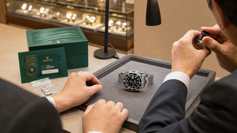 査定カウンターに置かれたシードゥエラーと保証書・箱・余りコマ。買取相場と付属品の有無が査定額を左右する実践場面を示す写真