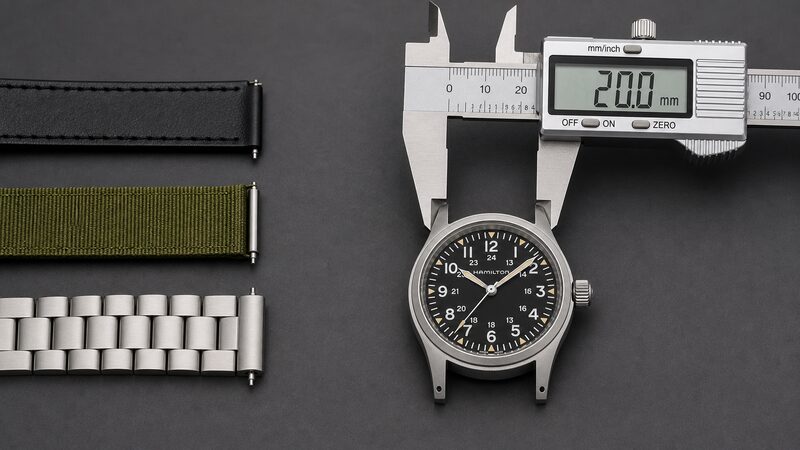 ストラップを外したカーキ フィールドのラグにノギスを当てて20mmを実測し、共有できる3本の20mmストラップ端を並べたマクロ写真