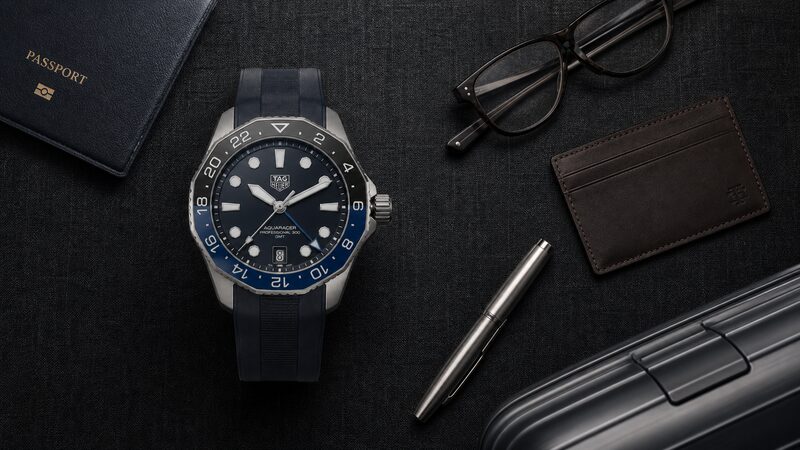 出張用の荷物とともに並べたタグホイヤー アクアレーサー プロフェッショナル300 GMT 42mmのチタンケースと濃色文字盤