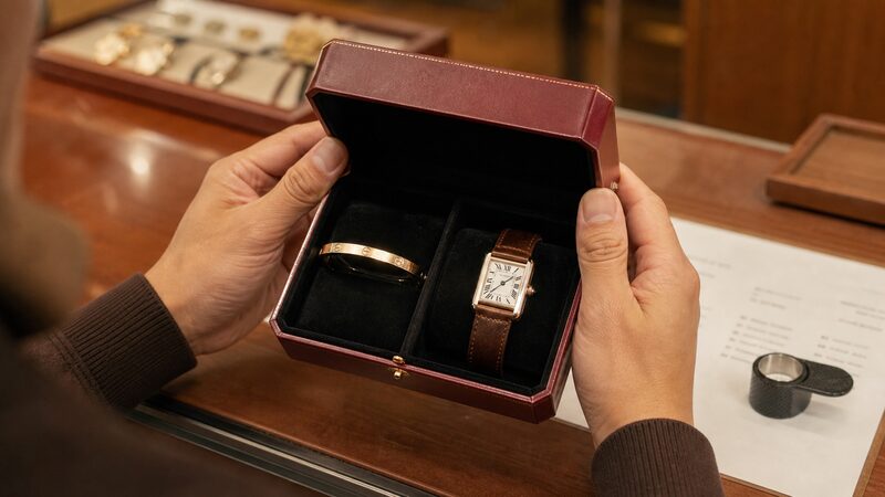 カルティエのLOVEブレスレットと時計を前に買い方や資産性を検討する男性の手元の様子