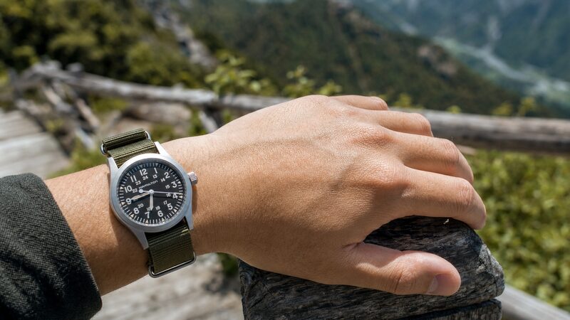 アウトドアのハイキングシーンでハミルトンカーキフィールドを着用する男性の腕元。タフな実用性を表現
