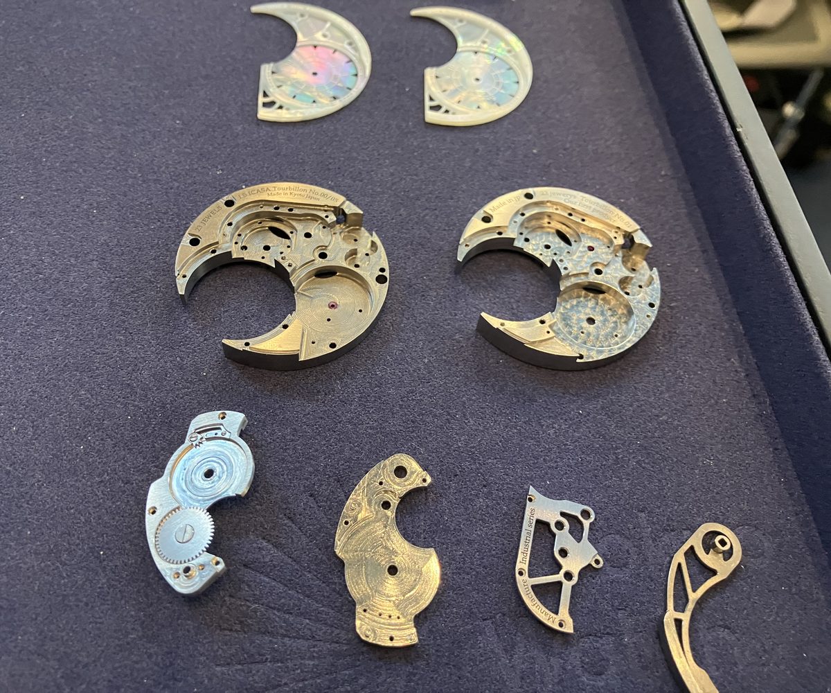 I.S.ICASAのトゥールビヨン用地板やブリッジなど、加工段階の異なる部品をトレイに並べた展示